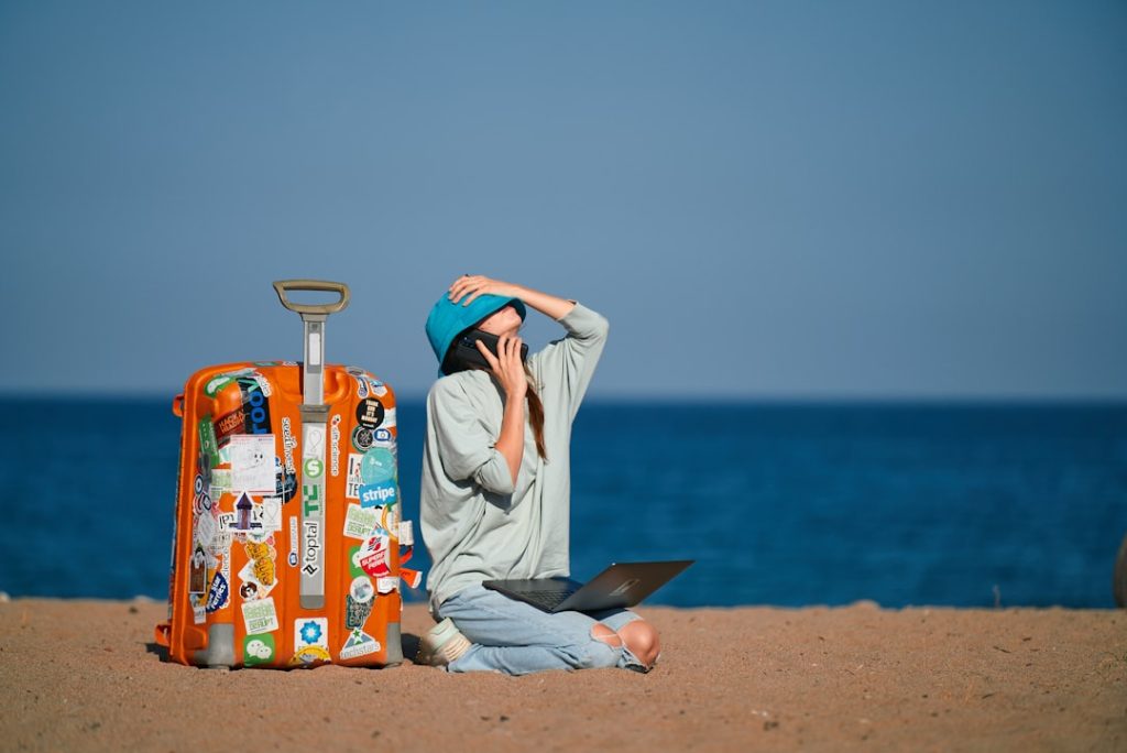 digital nomad worden — a person sitting on a beach with a suitcase and a laptop